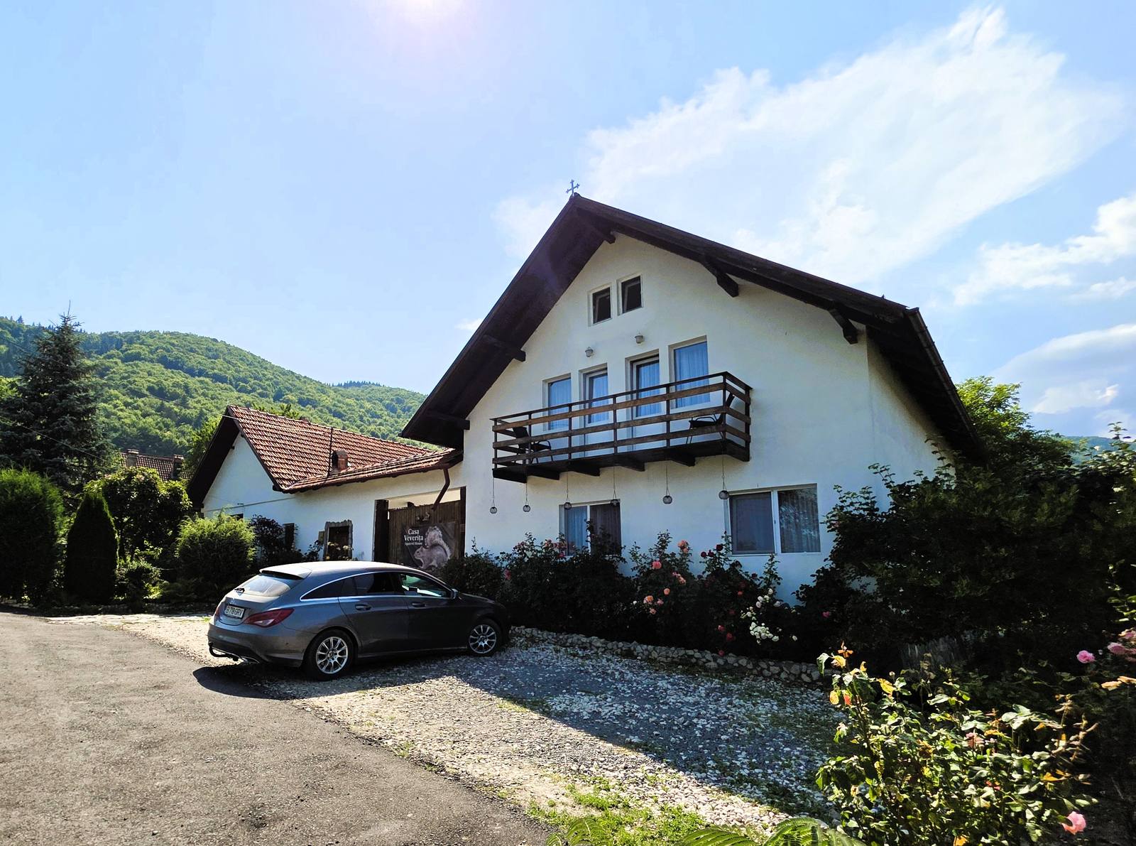 Clădirea pensiunii Casa Veverița, cu un deal împădurit în spate, în Predeluț